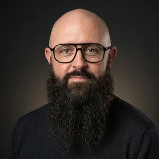 Portrait de Flavien Métivier, fondateur de The Bearded Bear : barbe longue, lunettes, sur fond sombre